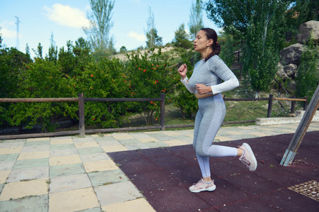 Woman in athletic wear running in a park, embracing an active lifestyle. Highlights outdoor...