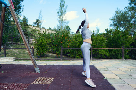 Woman exercising in a park, stretching in athletic wear, promoting a healthy lifestyle and fitness...