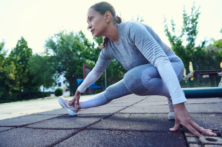 Woman stretching in park, preparing for a workout in sportswear. Outdoor exercise routine on a sunny...