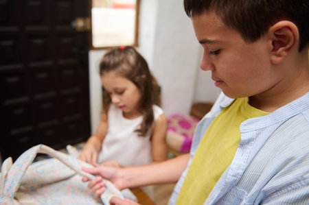 A young boy and girl are focused on packing a school bag together, showcasing teamwork and preparation in a home setting.の写真素材