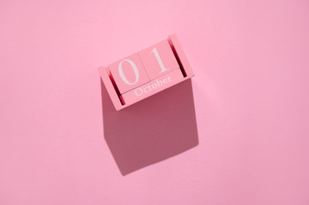 A pink calendar block shows October 1st on a matching pink background, evoking minimalism and simplicity.の写真素材