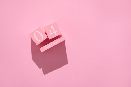 Wooden calendar blocks showcasing the date February 4th. Set against a pink background, creating a minimalistic and modern aesthetic.の写真素材