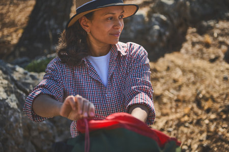 A woman in a plaid shirt enjoying a moment of tranquility during a hike in a sunny, serene natural setting.の写真素材