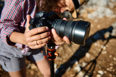 Close-up view of a photographer adjusting a camera on a tripod outdoors. Capturing a perfect shot in...