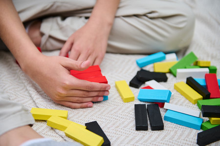 Child playing with colorful wooden blocks, organizing them in a playful and creative manner. The scene captures a moment of concentration and creativity on a soft carpet background.の写真素材