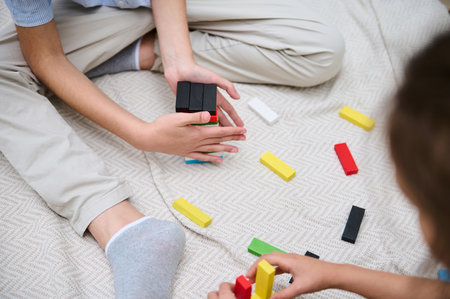 Children engaged in a playful and educational activity, using colorful building blocks on a soft carpet. This scene captures creativity, imagination, and teamwork as the kids build and have fun.の写真素材