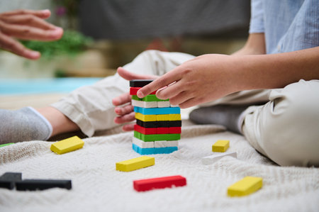 Two young people enjoy a fun and engaging stacking game on a cozy rug. The colorful blocks add vibrancy to the scene, emphasizing concentration, teamwork, and leisure. Ideal for depicting friendship, casual indoor activities, and playfulness.の写真素材