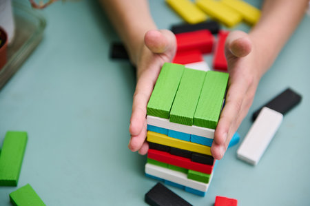 Close-up of hands expertly arranging a stack of vibrant wooden blocks on a table, showcasing...