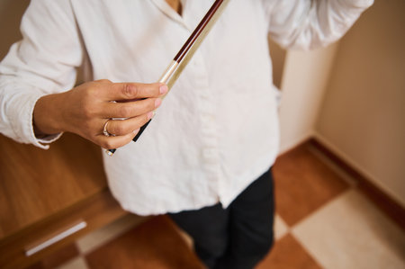 A detailed image showing a person delicately holding a violin bow. The focus is on the hand, showcasing the artistry and finesse required to play this classical instrument.の写真素材