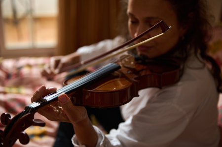 A close-up of a woman passionately playing the violin, emphasizing her skill and focus. The room is...