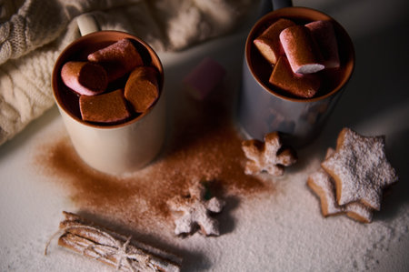 Warm winter scene with hot chocolate topped with marshmallows, surrounded by cookies and cozy elements, creating a comforting and festive atmosphere perfect for the holiday season.の写真素材