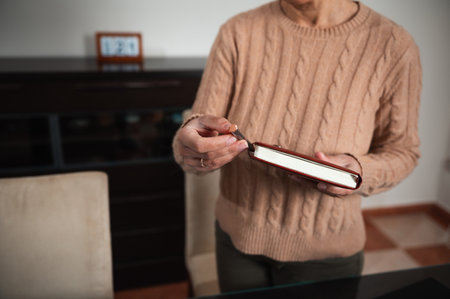 A person wearing a knit sweater holds a closed book, suggesting relaxation and leisure indoors.の写真素材