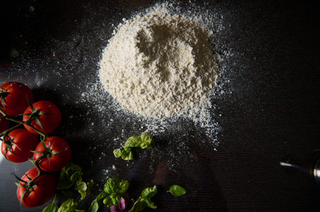 A pile of flour surrounded by ripe tomatoes and fresh basil leaves, ideal for pizza making or baking...