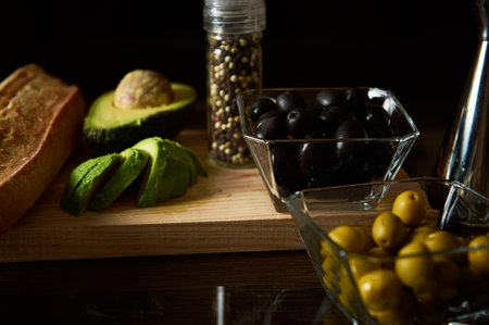 A selection of fresh ingredients including avocado, olives, and bread are artfully displayed on a...