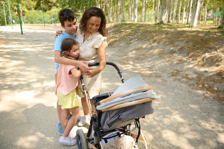A joyful family enjoys a sunny day in the park, bonding and strolling with a baby stroller. The...