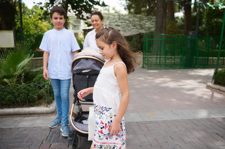 A family spending quality time outdoors, with children playing and strolling. Lush greenery surrounds them, providing a refreshing and joyful atmosphere, perfect for family bonding and relaxation.の写真素材