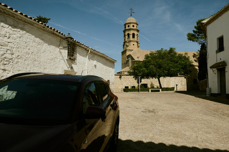 A charming village scene featuring a historic church tower and a parked car under bright sunlight. The rustic architecture adds a sense of timeless beauty to the peaceful setting.の写真素材