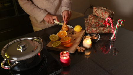 A cozy holiday scene with sliced fruits, candles, and wrapped gifts, evoking warmth and celebration.の写真素材