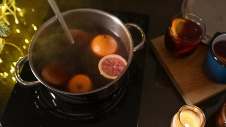 A steaming pot of mulled wine with oranges and lemons on a stove, creating a warm and festive atmosphere.の写真素材