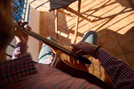 A cozy moment captured from above of a person strumming a guitar while enjoying a sunny day on a...