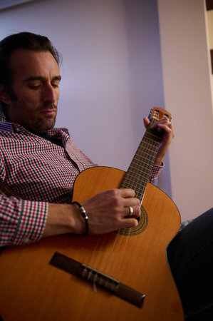 Someone wearing casual attire strumming an acoustic guitar, showcasing a moment of musical...