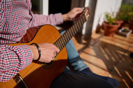 A person strumming an acoustic guitar while seated outside with sunlight. The soothing ambiance and...