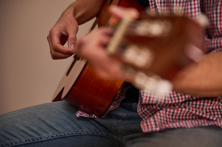 A seated individual strumming a classic acoustic guitar, highlighting hands and instrument details....