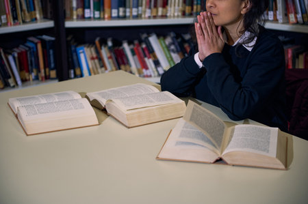 A focused individual sitting at a library desk with open books, symbolizing learning and research in...