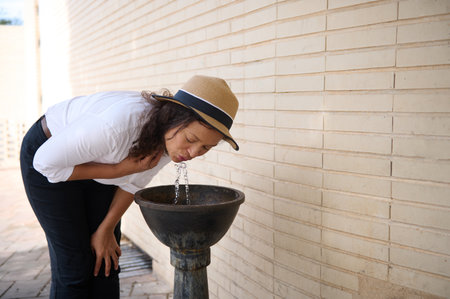 A woman captures the refreshing essence of hydration while enjoying a moment outdoors.の写真素材