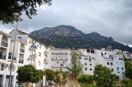 Mountain landscape framing a residential area under cloudy skies, showcasing urban living amidst natural beauty.の写真素材