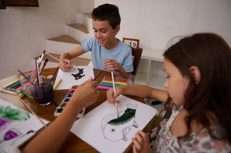 Three children engaging in a creative art activity, painting colorful illustrations and enjoying...