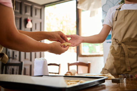 Two individuals are working together in a well-lit open kitchen preparing bakery goods.の写真素材