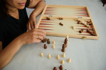 A person engaging with wooden board game pieces, utilizing strategic planning on a tabletop.の写真素材