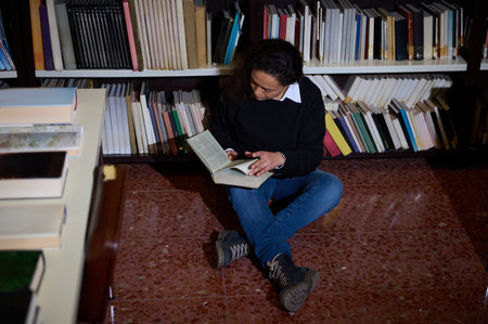 A serene moment of a person immersed in reading on the floor of a library, surrounded by shelves...