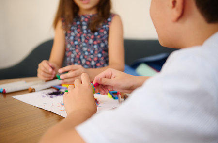 Children engaging in creative crafting activity with colorful materials on a table, fostering teamwork.の写真素材