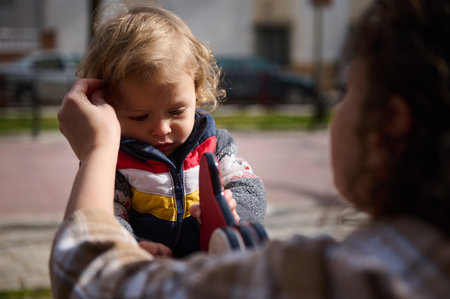 A scene depicting a mother aiding her child, showcasing care and love in an outdoor setting on a clear, bright sunny day.の写真素材