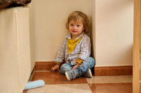 Young child indoors, seated in a corner, joyfully interacting. The playful environment and casual attire evoke innocence and comfort.の写真素材