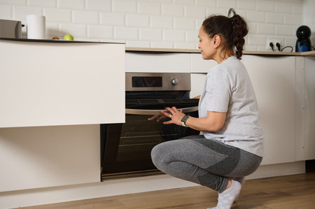 A woman sets the oven in a contemporary kitchen, surrounded by modern appliances in a calm moment.