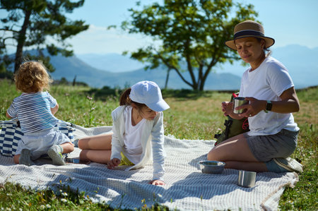 A family spends quality time having a picnic on a sunny mountain day, enjoying nature and bonding together in this peaceful outdoor setting.の写真素材