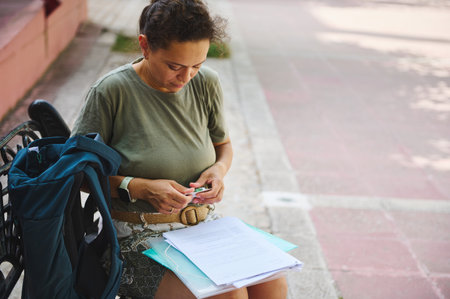 A woman engrossed in organizing documents on a bench, surrounded by natural light. Her focused...