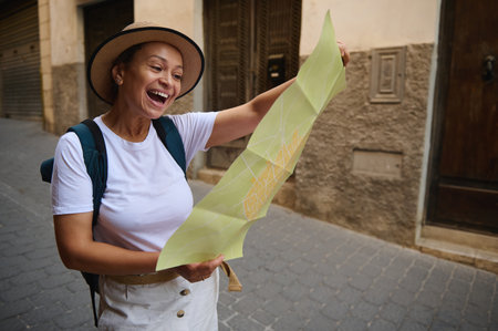A cheerful woman in summer attire enjoys exploring a historic town, navigating quaint narrow streets with her map in hand, embracing the joy of discovery and adventure.の写真素材