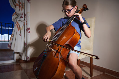 A diligent young instrumentalist practicing cello technique in a relaxed indoor setting, showcasing musical talent, concentration, and the pursuit of skill enhancement in an enjoyable environment.の写真素材