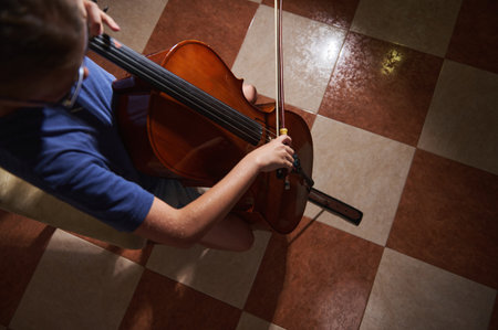 Focused view showing a musician performing on a cello with detailed hands' dynamic motion, set against tiled flooring, capturing artistry and instrument intricacies.の写真素材