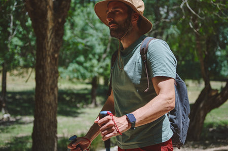 A bearded traveler enjoying an adventurous hike through verdant woodlands on a summer day. Showcasing an active lifestyle and exploration in a natural environment.の写真素材