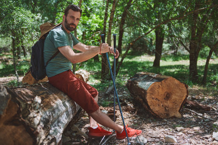 A bearded man hiking through a vibrant forest on a sunny day, showcasing his outdoor adventure surrounded by nature. Ideal image for travel and lifestyle concepts.の写真素材