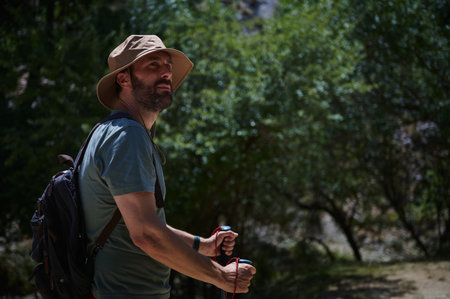 Middle-aged man trekking in a lush forested mountain area during a sunny day, indulging in physical activity and adventure, carrying hiking gear. Perfect for travel and adventure themes.の写真素材
