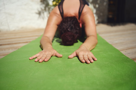 Practicing yoga in a serene outdoor setting on a green mat, embracing inner peace and relaxation during a sunny day.の写真素材