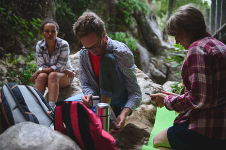 A group of friends resting amidst nature, surrounded by lush greenery and rocks, showcasing...
