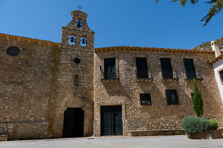 A charming building featuring rustic stone walls and a classic bell tower design showcasing historical architecture under a bright, cloudless day.の写真素材