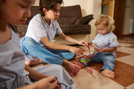 A group of children in a living room engaged in crafting with materials, showcasing creativity and teamwork. The scene portrays a warm home atmosphere and kids' collaboration.の写真素材